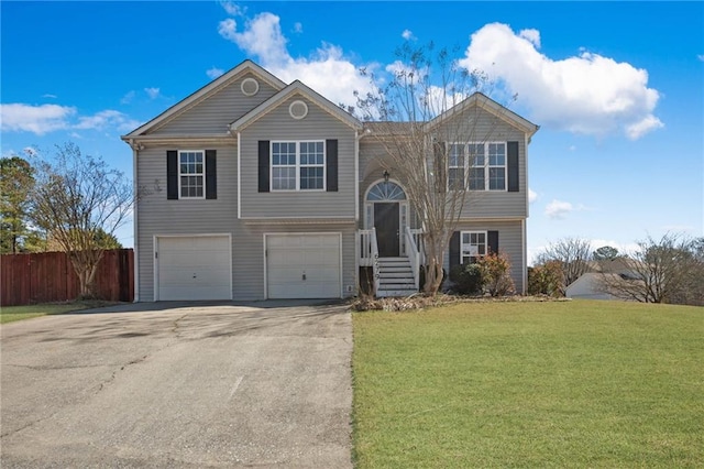 bi-level home featuring a front yard, fence, driveway, and an attached garage