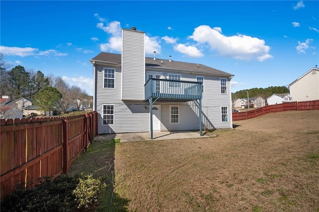 back of property featuring a fenced backyard, a lawn, a wooden deck, a chimney, and a patio area