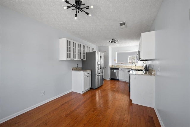 kitchen with visible vents, dark wood finished floors, glass insert cabinets, stainless steel appliances, and white cabinetry