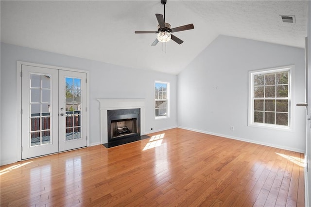 unfurnished living room with lofted ceiling, light wood finished floors, a fireplace with flush hearth, and visible vents