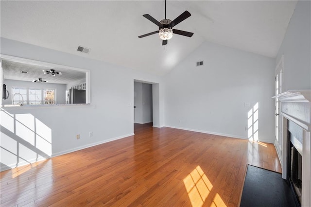 unfurnished living room with ceiling fan, wood-type flooring, a fireplace with flush hearth, and visible vents