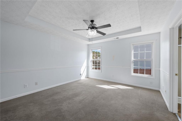 carpeted empty room with baseboards, a tray ceiling, ceiling fan, and a textured ceiling