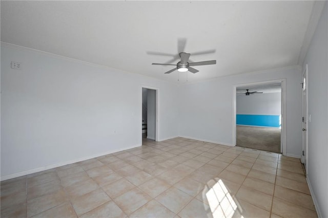 spare room featuring a ceiling fan, light tile patterned flooring, crown molding, and baseboards