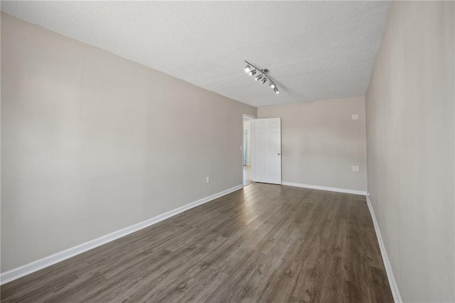 unfurnished room with rail lighting, a textured ceiling, baseboards, and dark wood-type flooring