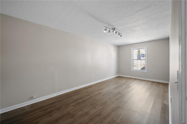 spare room with a textured ceiling, wood finished floors, and baseboards