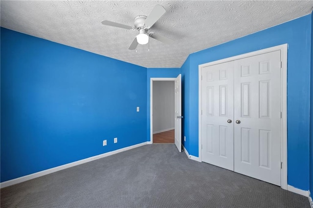 unfurnished bedroom with ceiling fan, a textured ceiling, baseboards, a closet, and dark colored carpet