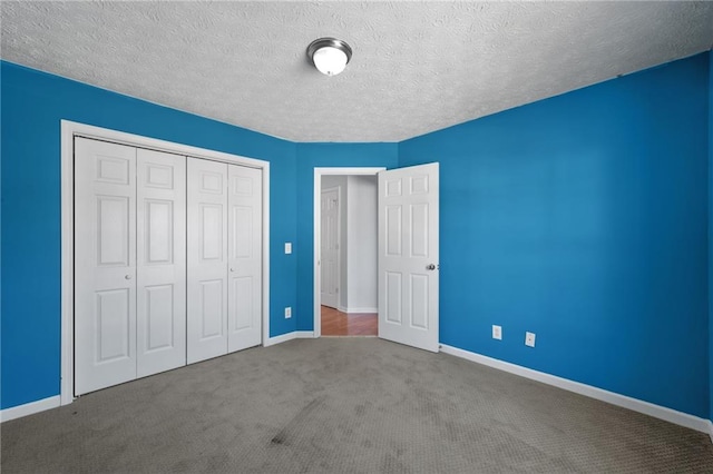 unfurnished bedroom featuring a textured ceiling, a closet, carpet flooring, and baseboards