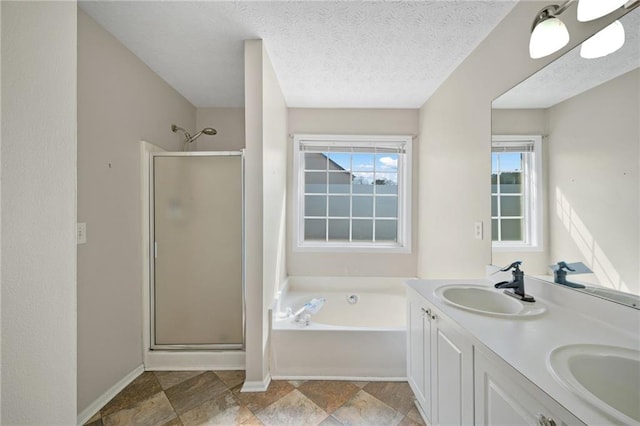 bathroom featuring a stall shower, a garden tub, a sink, and a textured ceiling