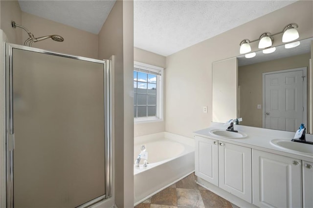 bathroom featuring a textured ceiling, a stall shower, a sink, and a bath