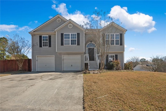 bi-level home featuring driveway, an attached garage, fence, and a front yard