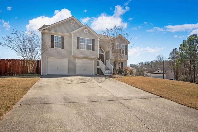 view of front of house featuring a garage, driveway, a front lawn, and fence