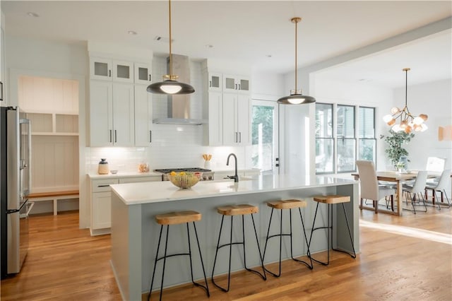 kitchen with stainless steel appliances, tasteful backsplash, light hardwood / wood-style floors, an island with sink, and white cabinets