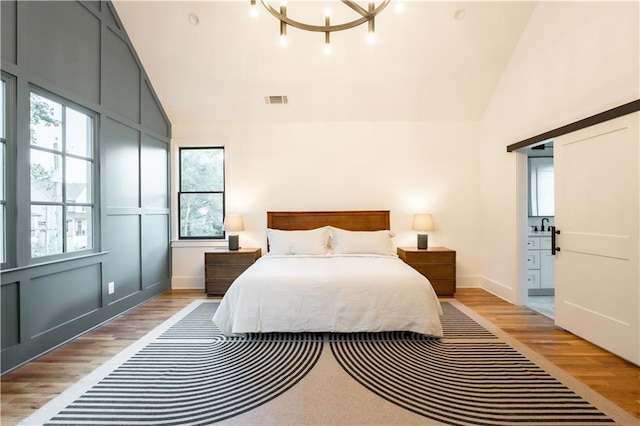 bedroom featuring high vaulted ceiling, a chandelier, and light hardwood / wood-style floors