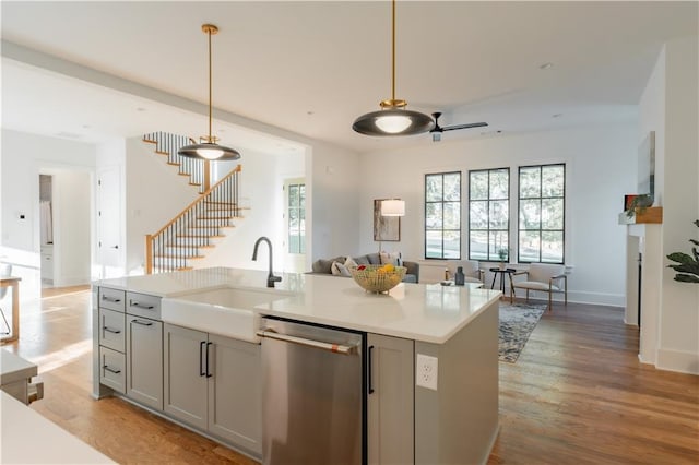 kitchen featuring pendant lighting, sink, a kitchen island with sink, gray cabinetry, and stainless steel dishwasher