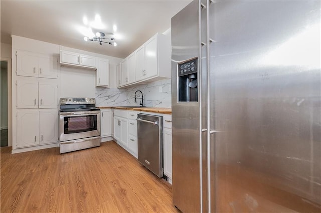kitchen featuring white cabinets, light wood-style flooring, a sink, and appliances with stainless steel finishes