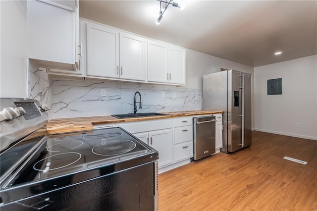 kitchen with electric panel, white cabinetry, wooden counters, appliances with stainless steel finishes, and a sink