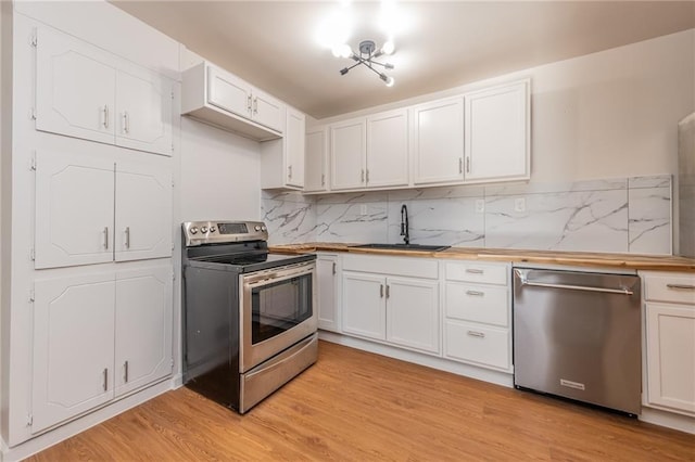 kitchen featuring light wood-style flooring, appliances with stainless steel finishes, a sink, and white cabinets
