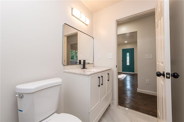 bathroom with toilet, wood finished floors, vanity, and baseboards