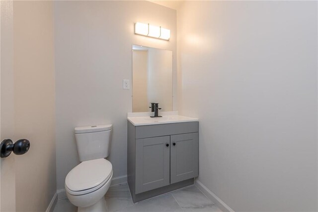 bathroom featuring toilet, baseboards, and vanity