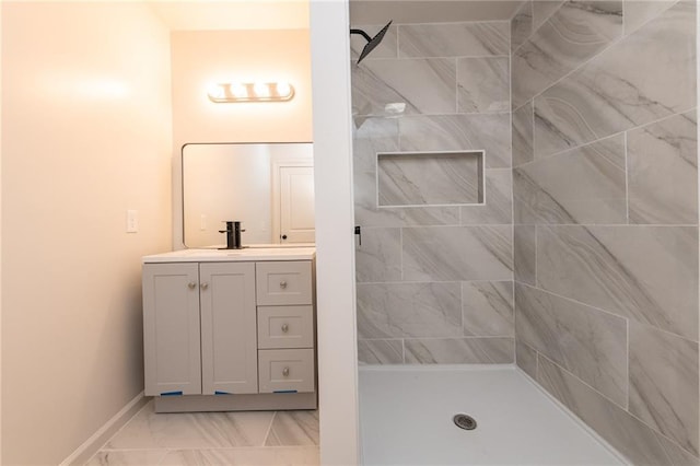 full bathroom with baseboards, tiled shower, marble finish floor, and vanity