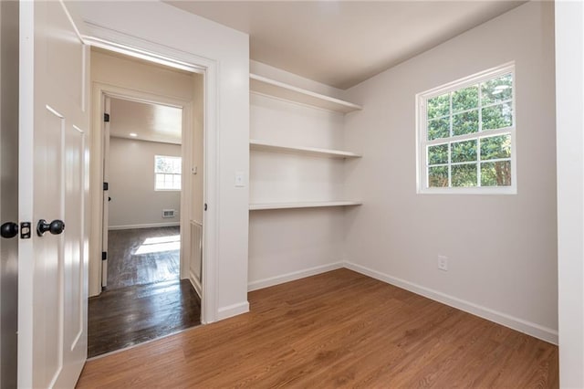 unfurnished room with wood finished floors, baseboards, and visible vents