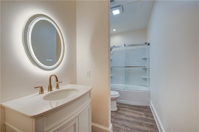 full bath featuring enclosed tub / shower combo, toilet, wood finished floors, vanity, and baseboards