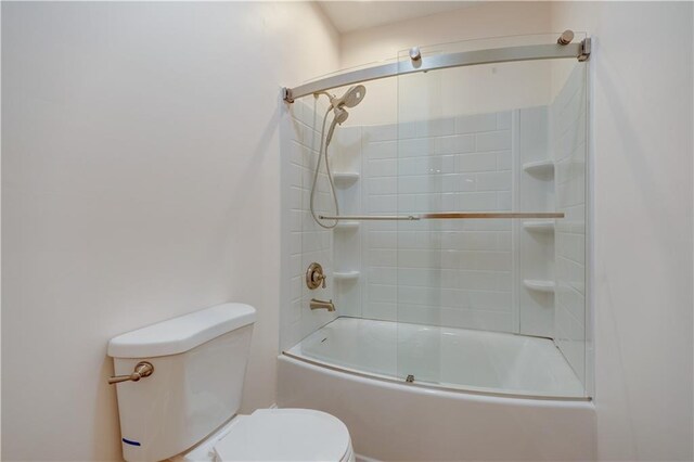 bathroom featuring toilet and shower / bath combination with glass door