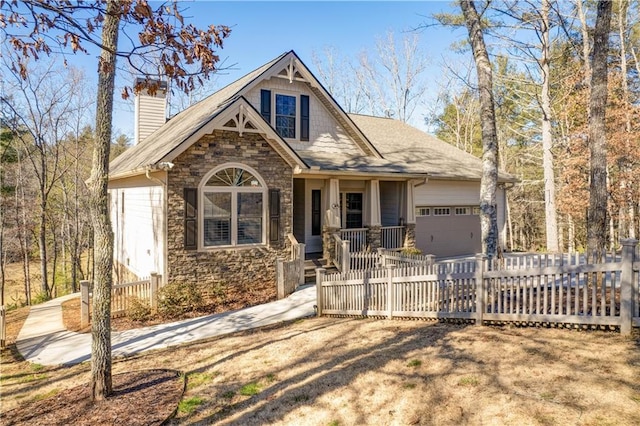 view of front of home with a garage, stone siding, a chimney, and fence