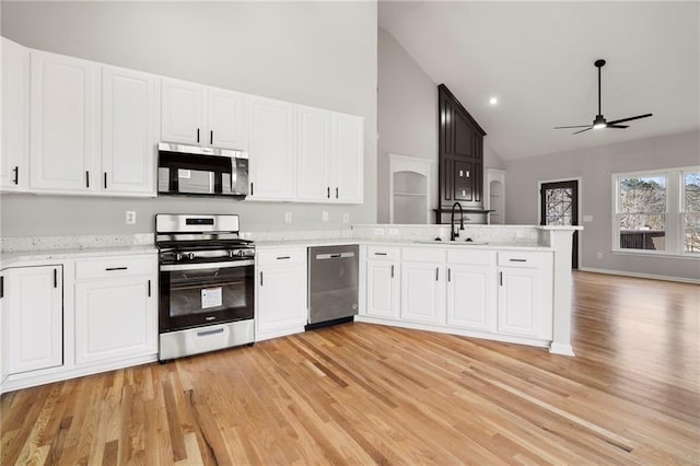 kitchen featuring sink, white cabinetry, light wood-type flooring, kitchen peninsula, and stainless steel appliances