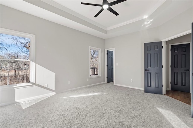 interior space with crown molding, ceiling fan, a tray ceiling, and carpet floors