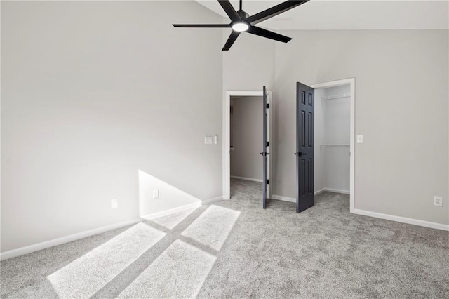 unfurnished bedroom featuring a spacious closet, high vaulted ceiling, light carpet, a closet, and ceiling fan