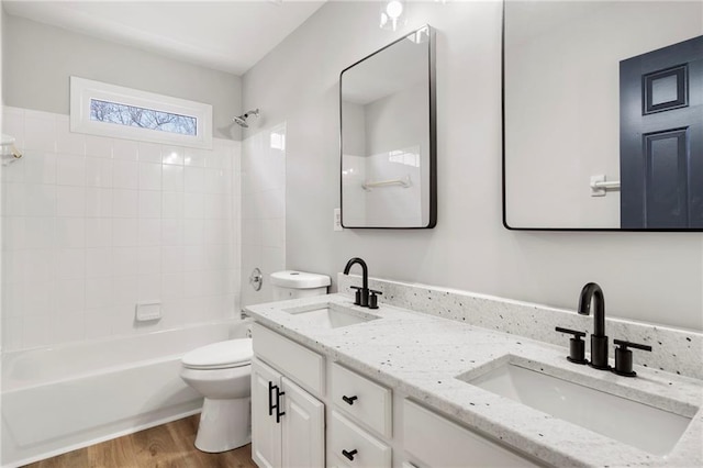 full bathroom with wood-type flooring, toilet, tiled shower / bath combo, and vanity