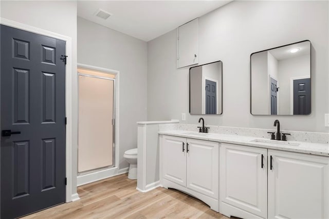 bathroom with wood-type flooring, toilet, a shower with door, and vanity