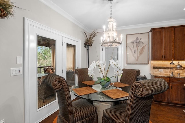 dining area featuring dark hardwood / wood-style flooring, crown molding, and a chandelier