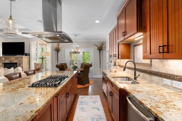 kitchen featuring island range hood, appliances with stainless steel finishes, pendant lighting, light stone counters, and sink