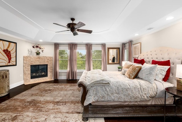 bedroom featuring ceiling fan, dark hardwood / wood-style flooring, crown molding, and a tray ceiling