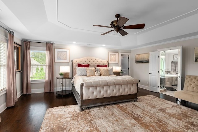 bedroom featuring dark hardwood / wood-style floors, ceiling fan, a raised ceiling, and ensuite bath