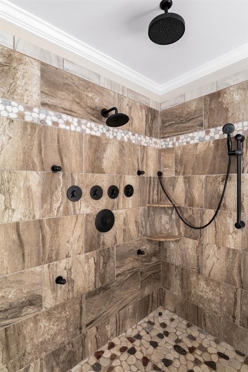 bathroom featuring tiled shower and crown molding