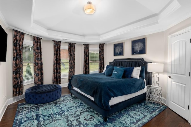 bedroom with crown molding, dark hardwood / wood-style flooring, and a raised ceiling