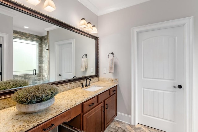 bathroom with a shower with door, vanity, and ornamental molding