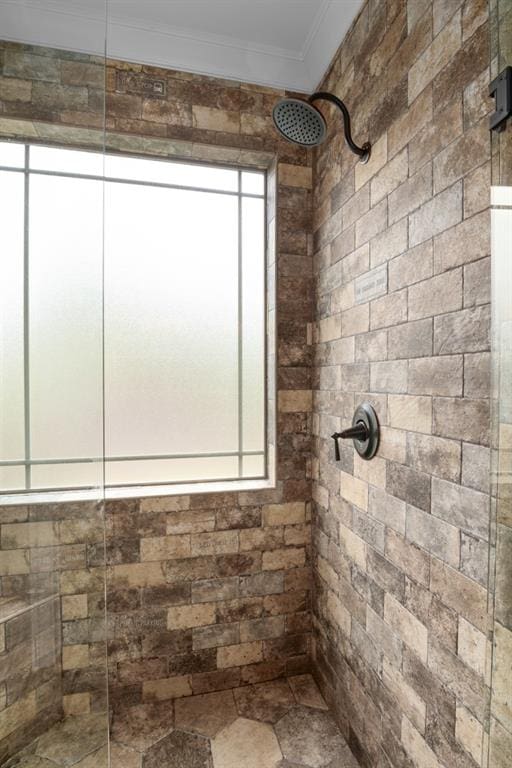 bathroom featuring ornamental molding and a tile shower