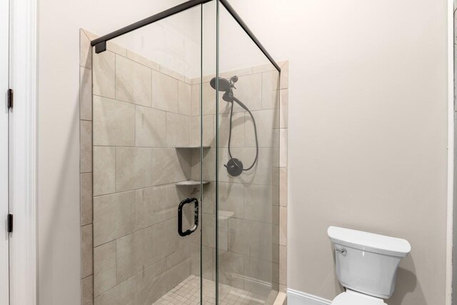 bathroom featuring toilet and a shower with door