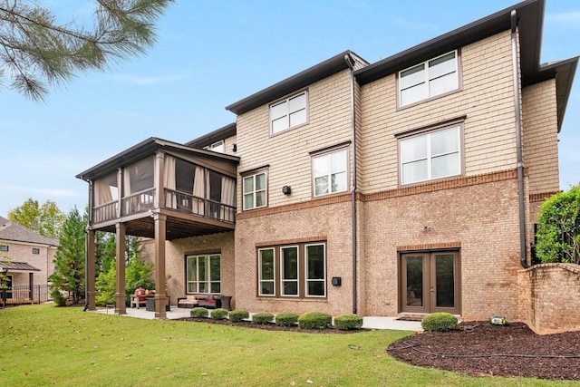 back of house featuring a lawn, french doors, a patio, and a sunroom