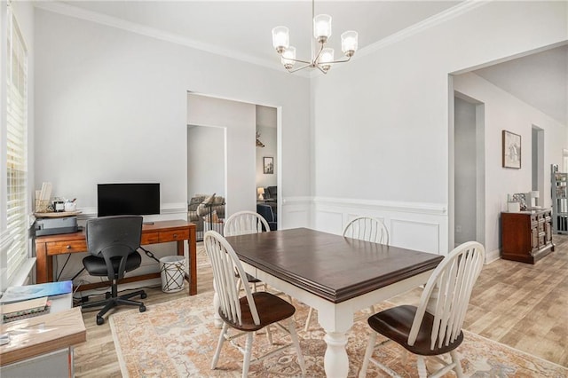 dining area with ornamental molding, wainscoting, a notable chandelier, and wood finished floors