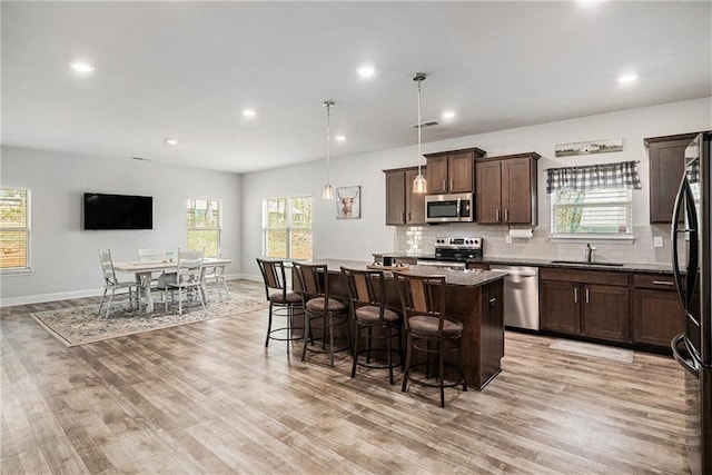 kitchen featuring a center island, a sink, light wood-type flooring, stainless steel appliances, and a breakfast bar area