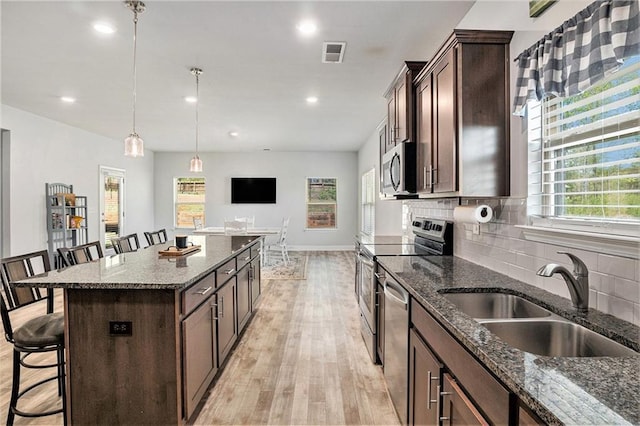 kitchen with a kitchen bar, tasteful backsplash, visible vents, a sink, and stainless steel appliances