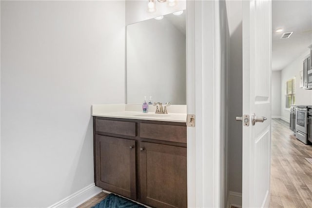 bathroom with vanity, baseboards, visible vents, and wood finished floors