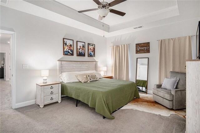 carpeted bedroom with visible vents, baseboards, ceiling fan, crown molding, and a tray ceiling