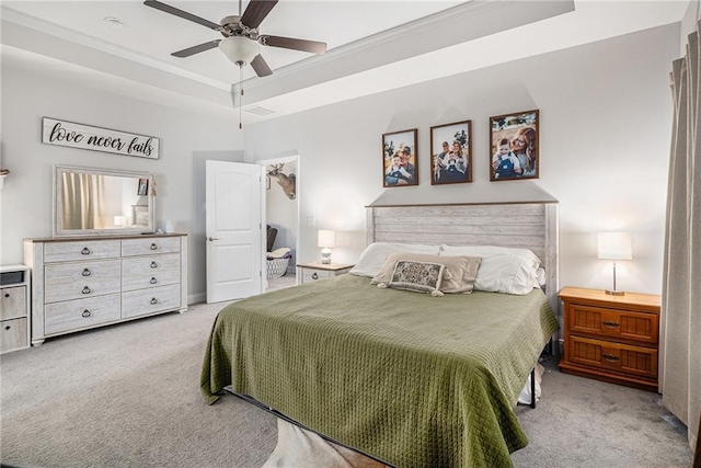 carpeted bedroom with a tray ceiling, ornamental molding, and a ceiling fan