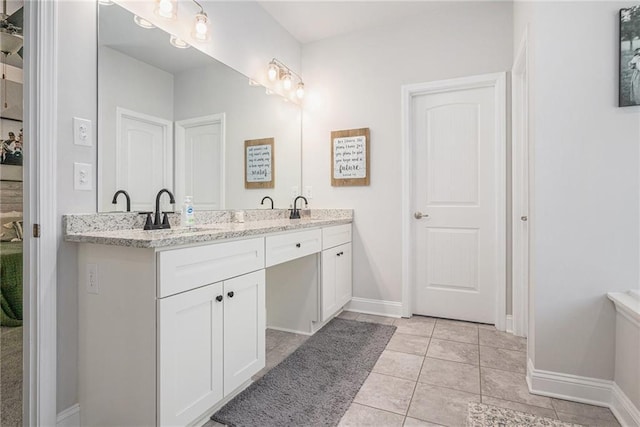 bathroom featuring tile patterned floors, double vanity, a sink, and baseboards